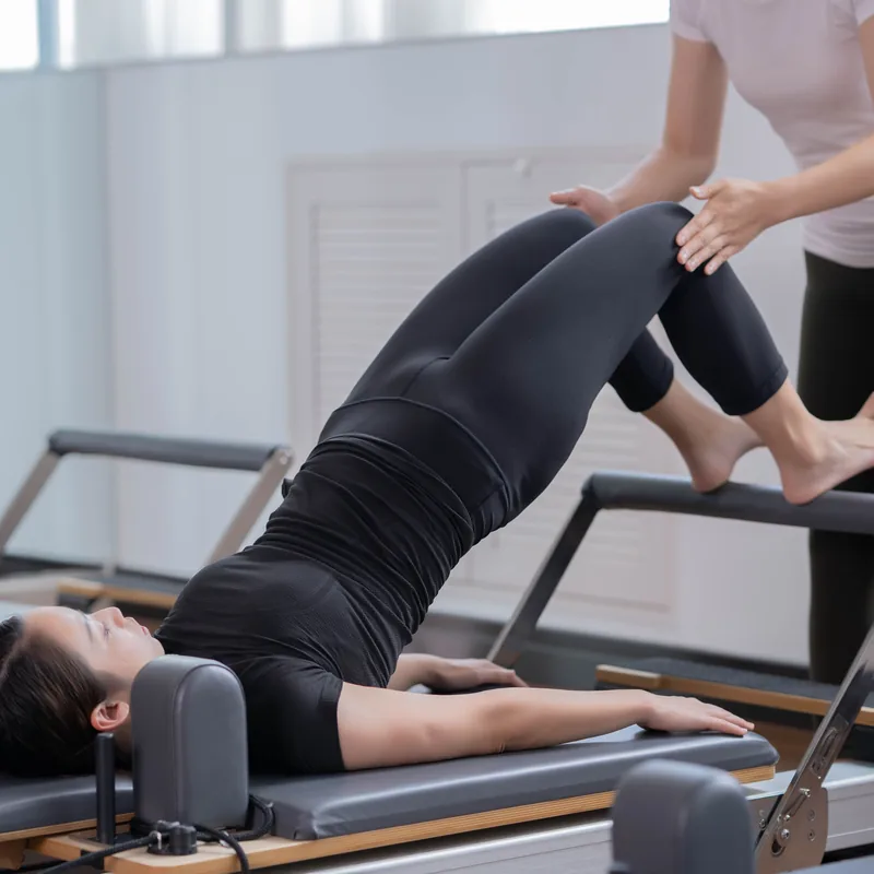 A teacher supporting a client's position on the reformer